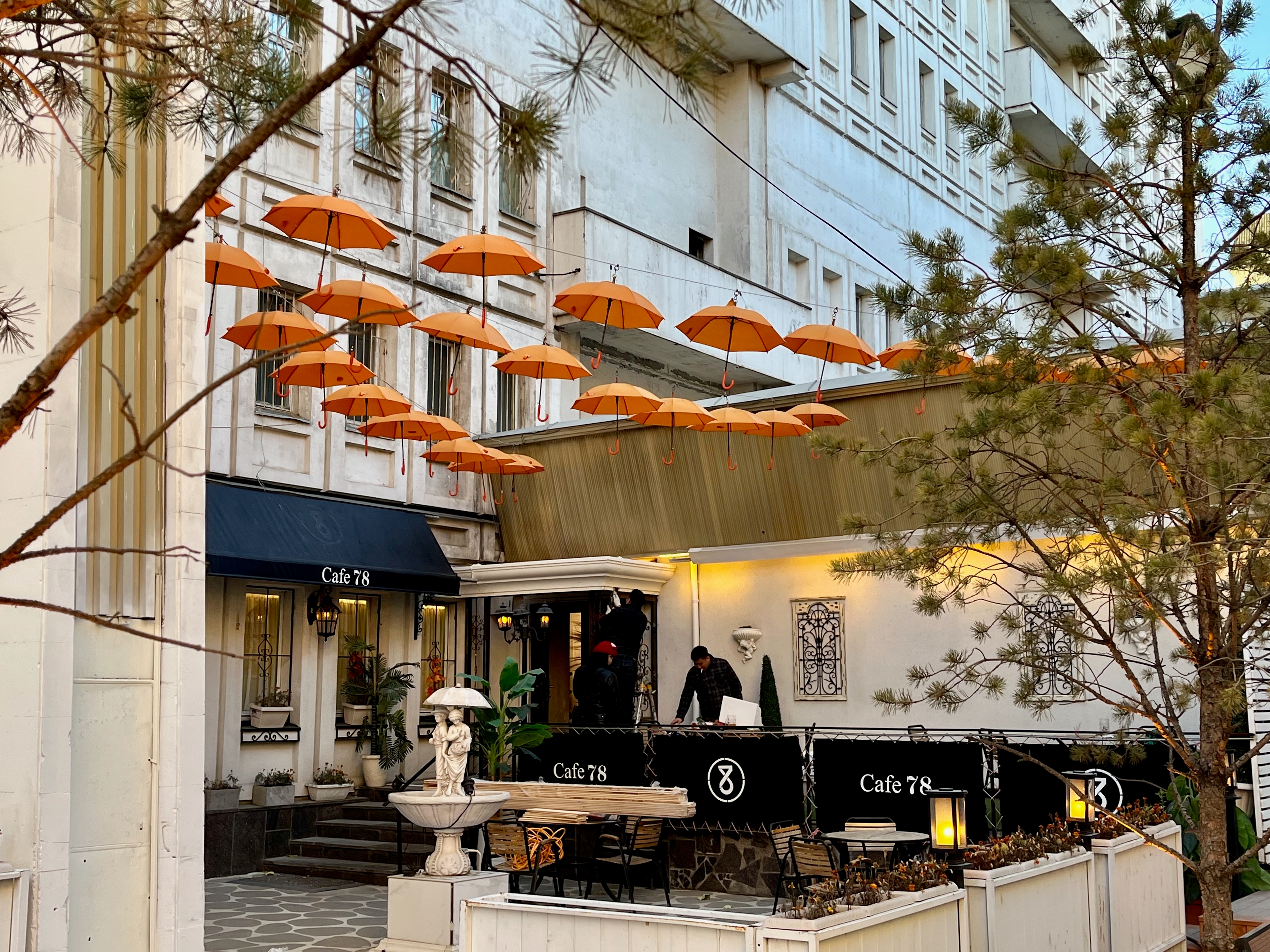 A cafe with orange umbrella decorations cleaning up after hours.